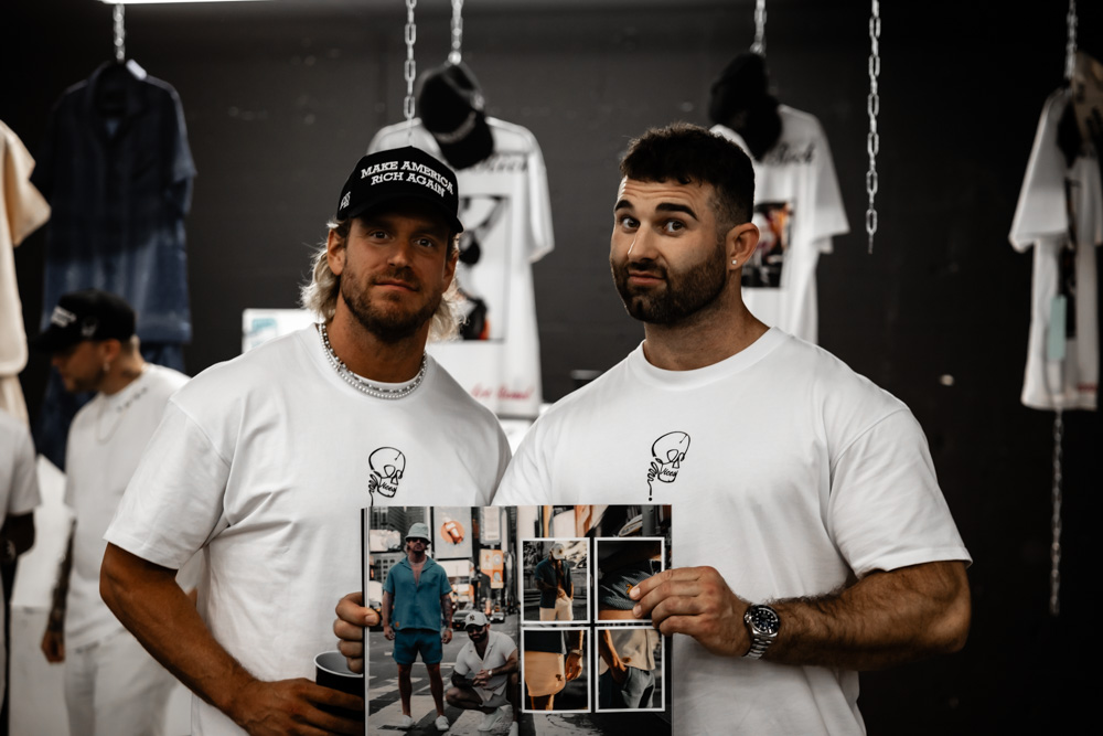 ViCES & Co. x Artlanta | Guests holding the capsule lookbook in front of the hanging apparel install